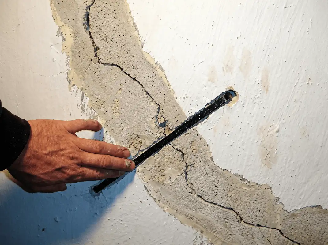 A wall with a large crack is being inspected by a professional in Columbia, MO