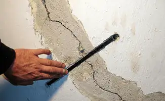 A wall with a large crack is being inspected by a professional in Columbia, MO